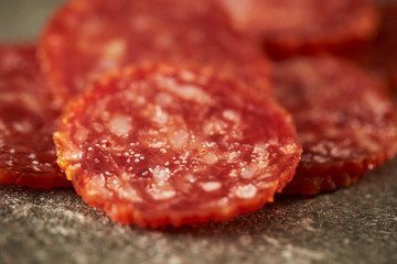 Thin sliced salami sausage on stone background 