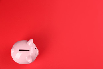 Pink piggy bank on red background, top view. Space for text