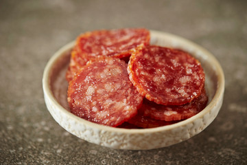 Thin sliced salami sausage on stone background 