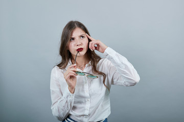 Attractive young brunette woman over isolated gray background wearing casual white shirt, holding...