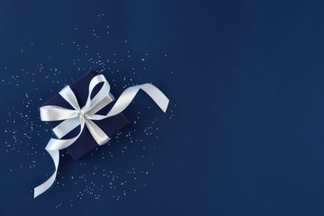 Gift box with bow and confetti on blue background  .Top view. Flat lay