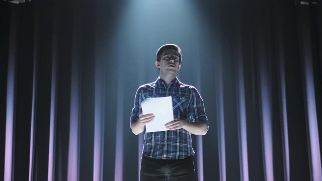 Medium shot of actors and actresses rehearsing a scene in a theater. Medium shot of an actor performing a monologue in a theater while holding his script