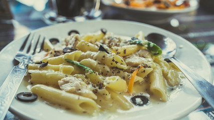 Pasta with white sauce with seafood, on a white plate with Cutlery