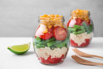 Healthy salad in glass jars on white table