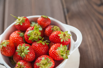Homemade strawberries in a white plate close-up and copy space.
