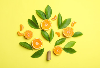 Flat lay composition with fresh green citrus leaves and tangerine slices on yellow background