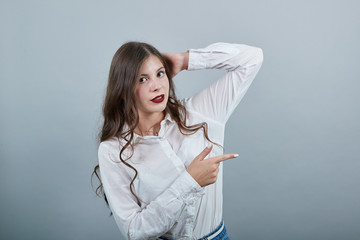Atractive young brunette woman over isolated gray background wearing casual white shirt, holding...