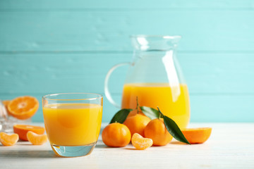 Glass of fresh tangerine juice and fruits on white wooden table