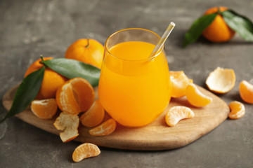 Fresh tangerines and glass of juice on grey table