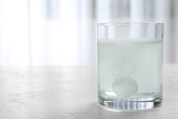Glass of water with effervescent tablet on light table indoors, space for text