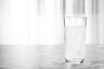 Glass of water with effervescent tablet on marble table indoors, space for text