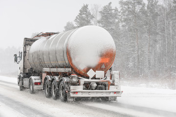 Fuel tanker truck on winter road. Blizzard.