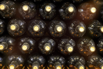 Bottles of white wine lie in a row on a shelf in the wine cellar. Closeup