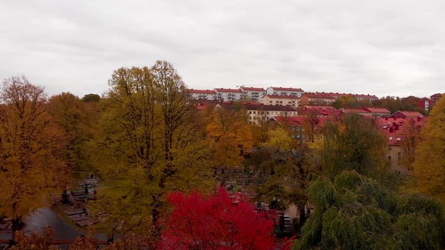 Aerial drone above Gothenburg graveyard, Sweden. Birds eye view of &ouml;stra Kyrkog&aring;rden cemetery with suburban view of red rooftops village. fall color trees over swedish scandinavian suburb neighborhood