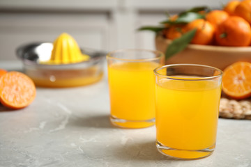 Glasses of fresh tangerine juice on marble table. Space for text