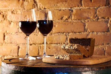 Two glasses of red wine, few pieces of rye bread, cheese and basil