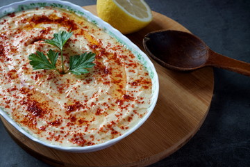 Hummus in a plate on a dark background