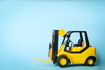 Toy forklift on blue background, space for text. Logistics and wholesale concept