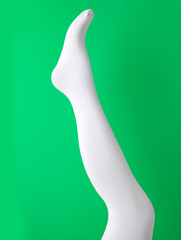 Leg mannequin in white tights on green background