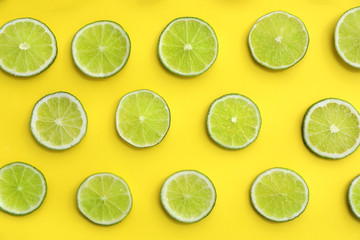 Slices of fresh juicy limes on yellow background, flat lay