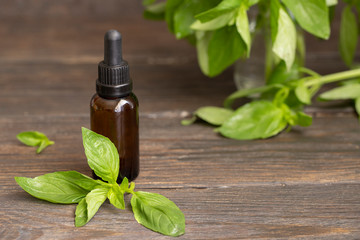 Fresh parsley leaves and parsley essential oil in a glass bottle on wooden background. Natural medicine and aromatherapy