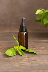 Fresh parsley leaves and parsley essential oil in a glass bottle on wooden background. Natural medicine and aromatherapy