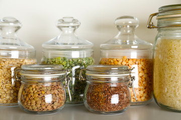 Different types of legumes and cereals in jars on table. Organic grains