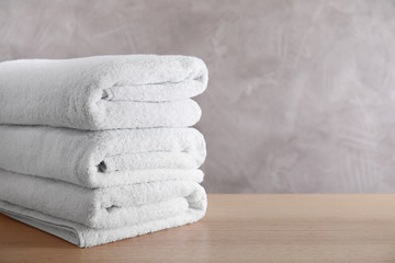 Stack of clean bath towels on wooden table. Space for text