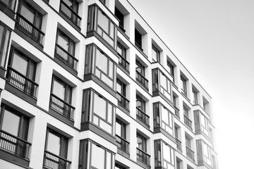 Sun rays light effects on urban buildings. Fragment of modern residential apartment with flat buildings exterior. Detail of new luxury house and home complex. Black and white.