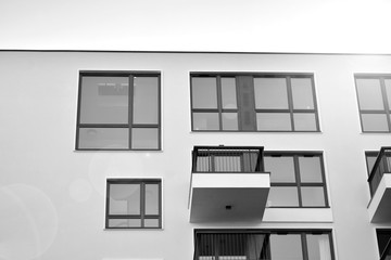 Sun rays light effects on urban buildings. Fragment of modern residential apartment with flat buildings exterior. Detail of new luxury house and home complex. Black and white.