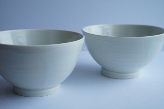 Closeup Shot Of Two Identical White Ceramic Bowls With A Blurred Grey Background