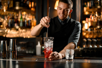 Bartender stirring alcohol drink with a bar spoon
