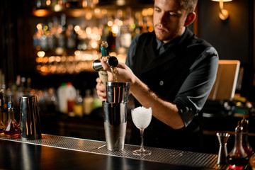 Bartender pouring scotch from jigger to shaker