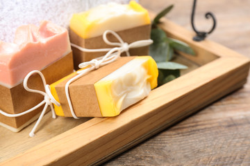 Fototapeta na wymiar Natural handmade soap bars in tray on wooden table, closeup