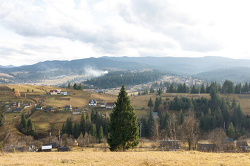 Fototapeta premium The wonderful landscape of the foggy mountain and forest and the small village under it