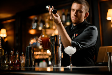 Bartender flowing liquor from jigger to shaker
