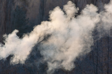 Smoke from the chimney of a house at dawn of the sun