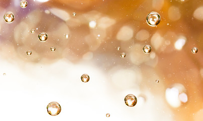 Bubbles of air on the smooth surface of golden water as an abstract background