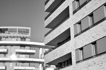 Sun rays light effects on urban buildings. Fragment of modern residential apartment with flat buildings exterior. Detail of new luxury house and home complex. Black and white.