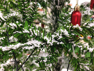 Artificial Christmas tree decorated with red, cylindrical matt glass jewellery with a gold chain on...