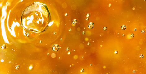 Bubbles of air on the smooth surface of golden water as an abstract background