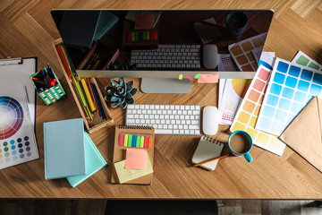 Designer's workplace with modern computer and color palettes, flat lay