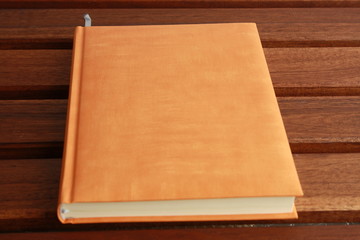 book with orange cover on wooden background