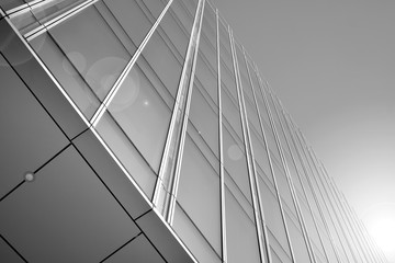 Sun rays light effects on urban buildings in sunset. Modern office building detail, glass surface with sunlight. Business background. Black and white.