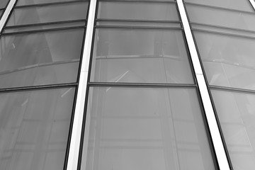 Obraz premium Sun rays light effects on urban buildings in sunset. Modern office building detail, glass surface with sunlight. Business background. Black and white.