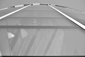 Obraz premium Sun rays light effects on urban buildings in sunset. Modern office building detail, glass surface with sunlight. Business background. Black and white.