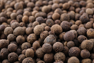 Black pepper grains as background, closeup view