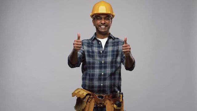 profession, construction and building - happy smiling indian worker or builder in helmet showing thumbs up over grey background