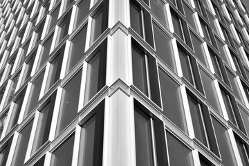 Obraz premium Sun rays light effects on urban buildings in sunset. Modern office building detail, glass surface with sunlight. Business background. Black and white.