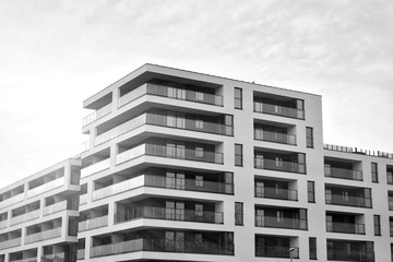 Fototapeta premium Sun rays light effects on urban buildings. Fragment of modern residential apartment with flat buildings exterior. Detail of new luxury house and home complex. Black and white.